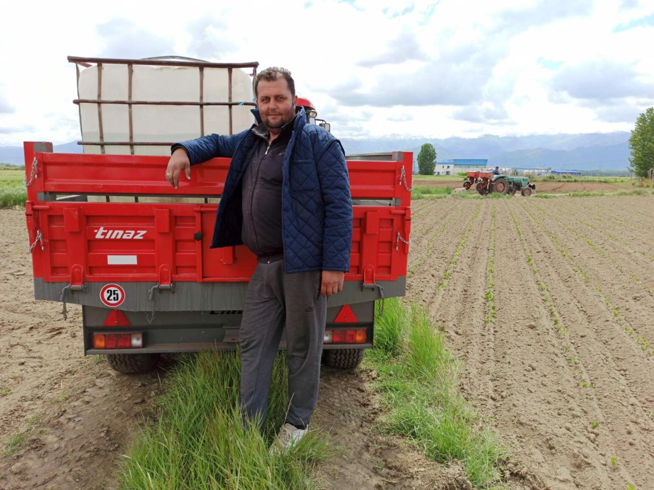 A farmer standing in front of a vehicle on a field